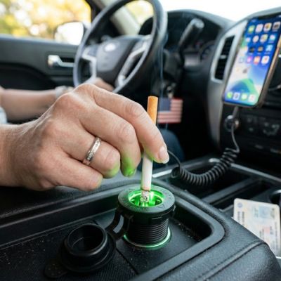 Conducteur allume son cigare avec prise allume cigare installé et charge smartphone